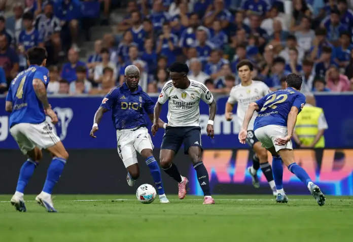 Vinicius rodeado por jugadores del Real Oviedo tras salir desde el banquillo.