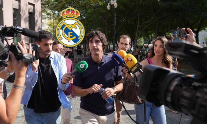 Javier Enríquez Negreira hablando ante los medios de comunicación y el escudo del Real Madrid. 